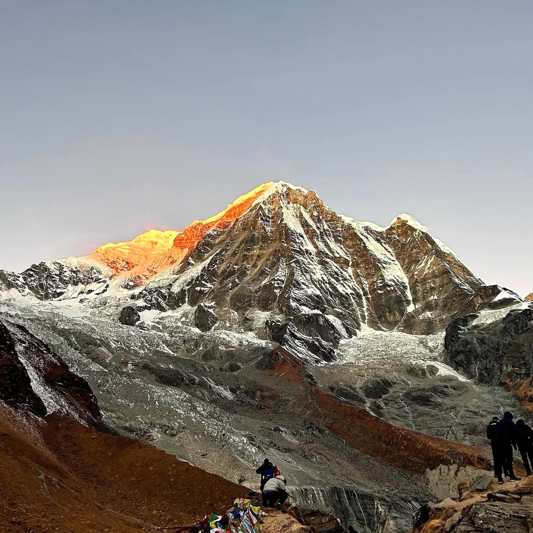 Trekkers at Annapurna Base Camp at sunrise with Annapurna South in the background